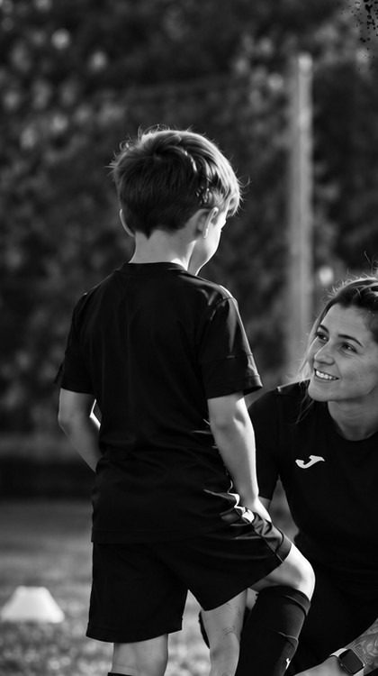 East & 11th Academy coach lacing up a young football player's boots